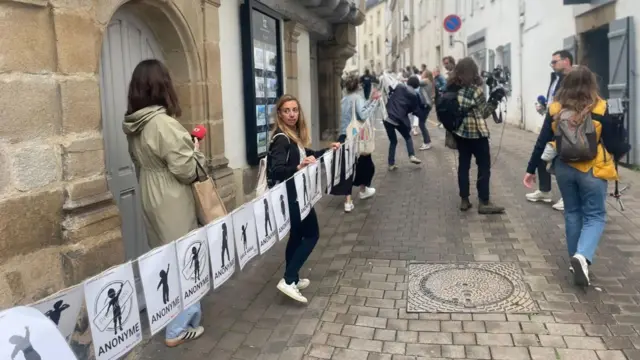 У середу біля будівлі суду розгорнули довгий банер, що демонструє численних жертв Ле Скуарнека