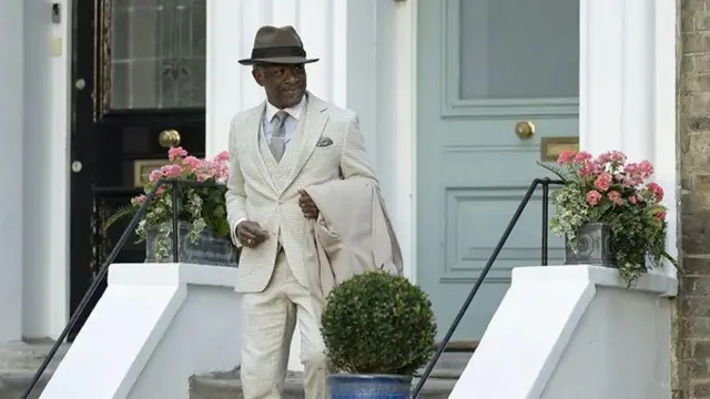 Кадр із серіала "Містер Ловерман". Літний чоловік в елегантному білому костюмі спускається сходами на виході з будинку