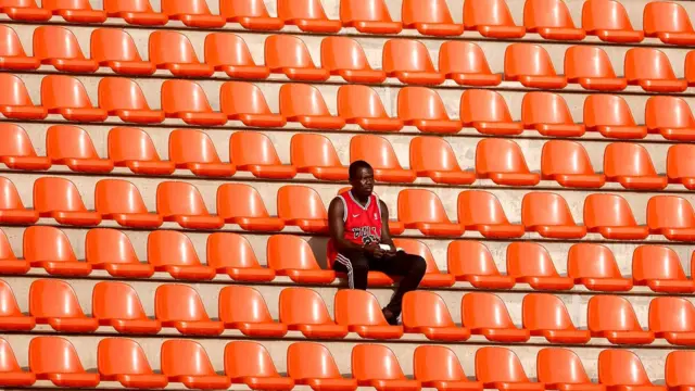 Homem sentado em arquibancada vazia