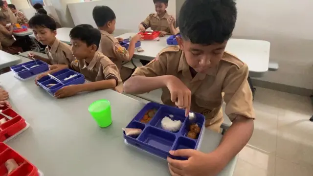Para murid SD Al Muttaqin duduk di meja makan yang telah diatur penempatannya sesuai kelas. Setelah berdoa, mereka langsung menyantap sajian di depannya.