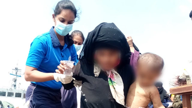 படகில் இருந்து கைக்குழந்தையுடன் மீட்கப்படும் பெண்