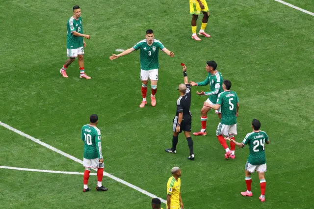 لاعبون من منتخب المكسيك قرب الحكم لحظة إصداره بطاقة حمراء بحق أحد اللاعبين.