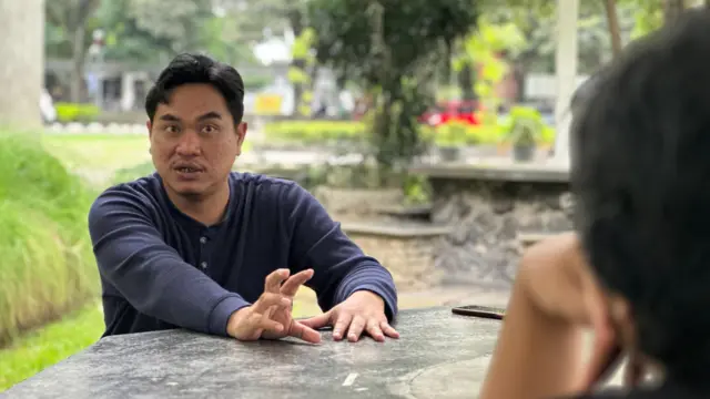 Agung Wardana sedang mengobrol dengan rekannya di sebuah taman di Fakultas Hukum UGM.