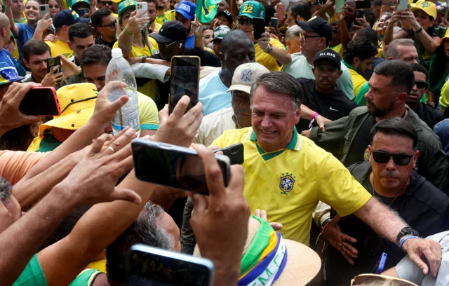 Bolsonaro, com camisa do Brasil, rodeado por apoiadores