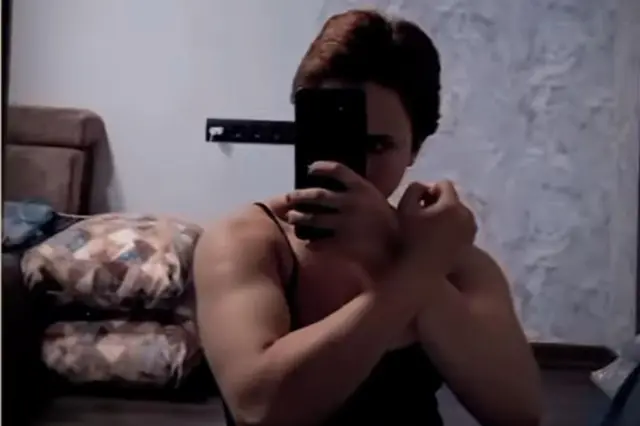 Айшат делает селфи на телефон, демонстрируя бицепсы