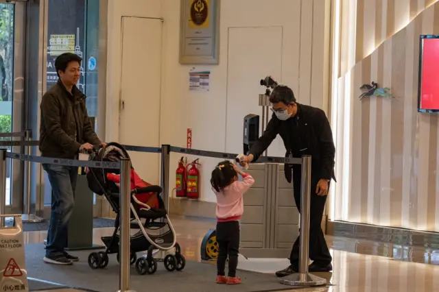 圖為2020年4月新冠疫情之初,台灣高鐵職員為一名兒童乘客量體溫