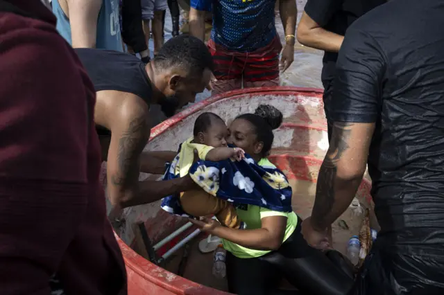 Mulher sendo resgatada com filha bebê