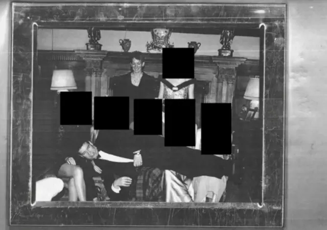 Uma imagem em preto e branco mostrando Andrew deitado no colo de mulheres