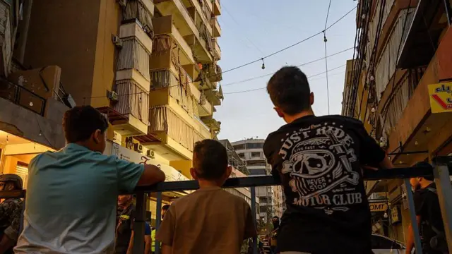 Местные жители смотрят на дом, который пострадал при израильском ударе