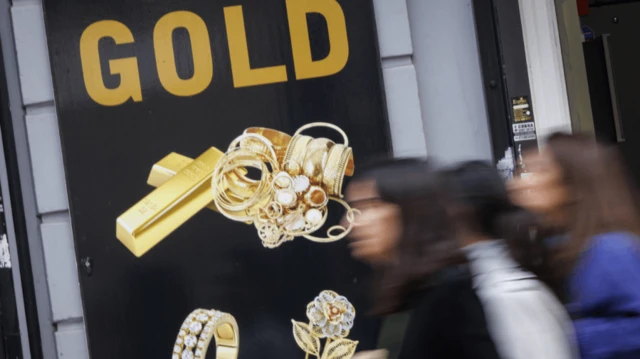 Un cartel en la calle anuncia "oro" mientras la gente para por delante.