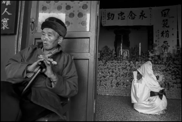 장례식이 진행되고 있는 곳 앞에 앉아 있는 노인