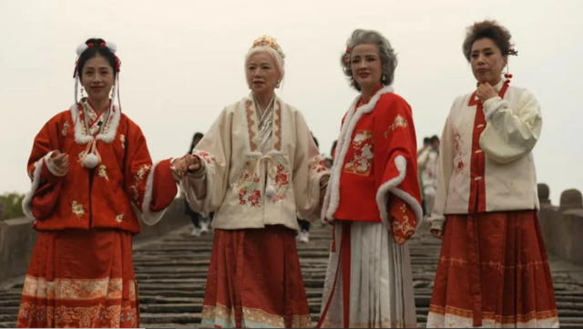 Quatro mulheres com trajes típicos sorrindo em escadaria