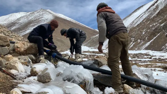 İşçiler dağın zirvelerinden vadiye su getirmek için borular monte ediyor