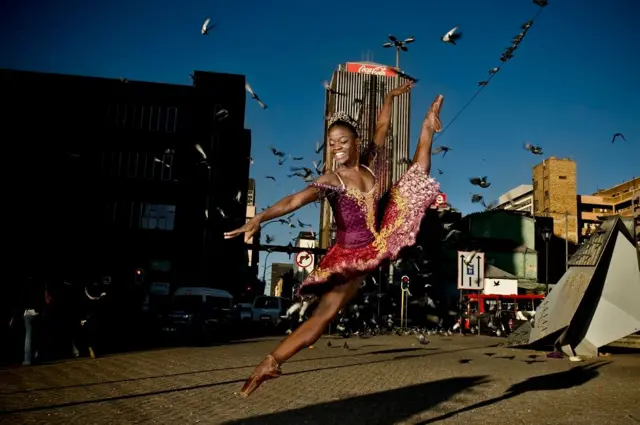 DePrince con un tutú rojo bailando en la calle.