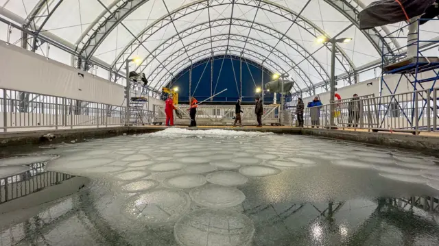 A imagem mostra o novo Observatório Marinhoblackjack betfairChurchill, com uma estrutura coberta, onde cientistas estudam a água da Baíablackjack betfairHudsonblackjack betfairduas piscinas experimentais. O ambiente contém gelo na superfície das piscinas e pessoas trabalhando ao fundo.