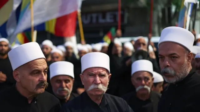 رجال دين دروز يحملون لافتات خلال مظاهرة تضامنية مع المجتمع الدرزي من مدينة السويداء جنوب سوريا في 19 يوليو/تموز