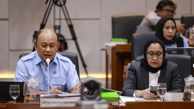 Kepala Badan Gizi Nasional (BGN) Dadan Hindayana (kiri) bersama Wakil Kepala BGN Nanik S. Deyang (kanan) menyampaikan paparan pada Rapat Dengar Pendapat (RDP) dengan Komisi IX DPR di Kompleks Parlemen, Senayan, Jakarta, Rabu (12/11/2025).