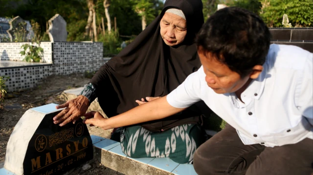 Diah Eka Sari (kiri) bersama adiknya, Pangestu Murwandani (kanan) di pusara ayah mereka.
