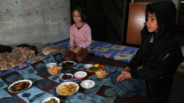 طفلان سوريان على مائدة طعام متواضعة على الأرض
