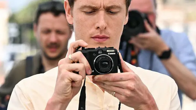 Британський актор Гарріс Дікінсон з компактною фотокамерою на Каннському кінофестивалі 2025 року
