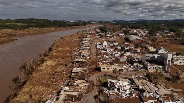 Imagem área deuma cidade na beira de um rio devastada após enchentes 