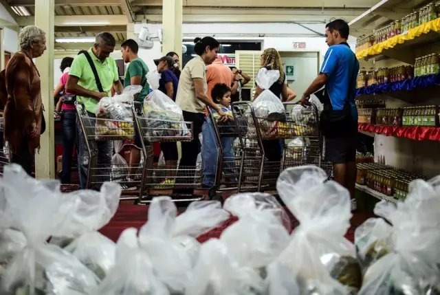 Personas haciendo cola para comprar alimentos en un supermercado en Caracas.