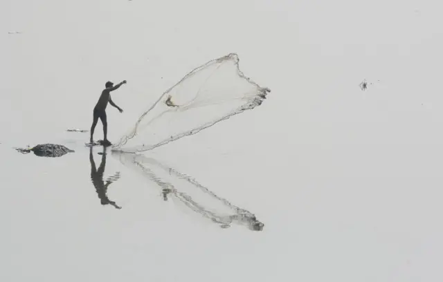 एक मासेमार जाळे टाकताना