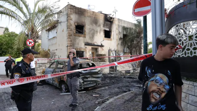 صورة لفرق الطوارئ الإسرائيلية وهي تغلق موقع هجوم صاروخي على حي سكني في شمال إسرائيل بكردون أمني.