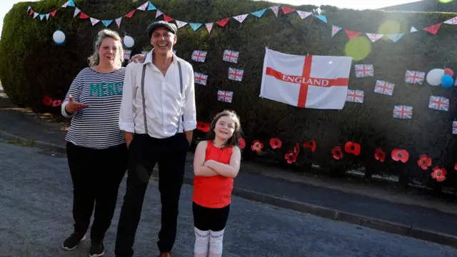 Три человека на фоне украшенного забора