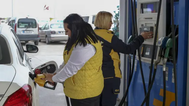 İKi kadın görevli istasyonda, biri araca benzin dolduruyor diğer fiş kesiyor.