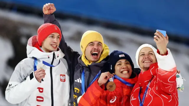 4人が横並びで笑顔を見せている。デシュバンデンが自撮りしている