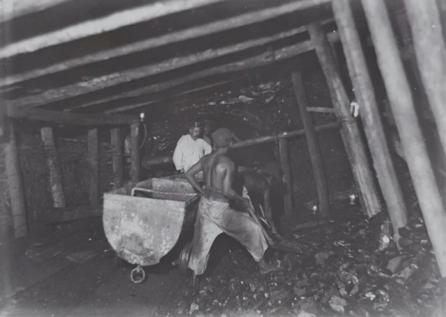 Para pekerja tambang batu bara Ombilin di Sawahlunto yang bekerja diawasi mandor mereka, sekitar tahun 1910.