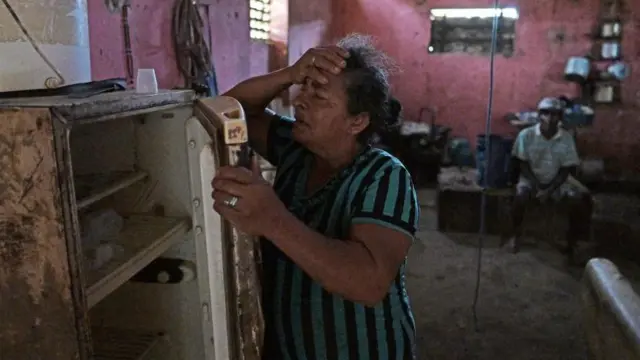 Una mujer abre su refrigerador mostrando que está vacío.