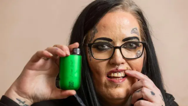 ستايسي غاردينر تُظهر أسنانها حيث تظهر نقاط سوداء فوق سنيّها العلويَين