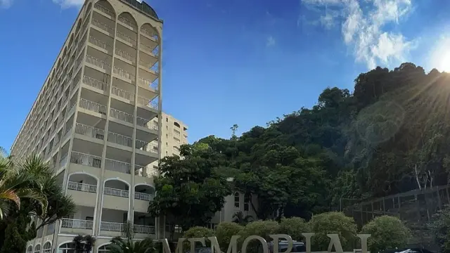 Fotografia colorida mostra um prédioinstalar o esporte betdez andares sob um céu azul ao ladoinstalar o esporte betárvores verdes