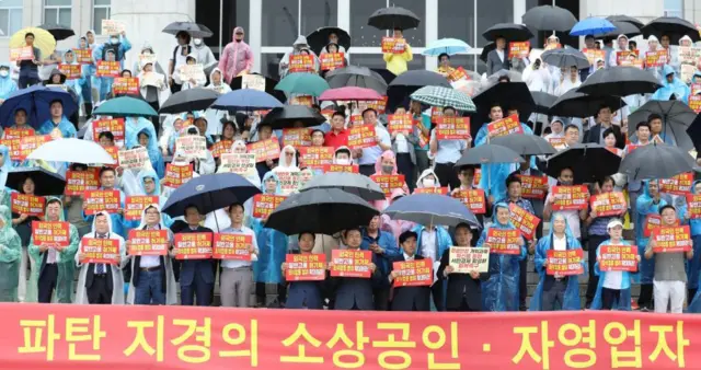 한국외식업중앙회 소속 회원들이 2023년 6월 20일 서울 여의도 국회 본청 앞에서 열린 자영업자·소상공인 생계 회복 촉구 기자회견에서 최저임금 인상 반대 등 구호를 외치고 있다