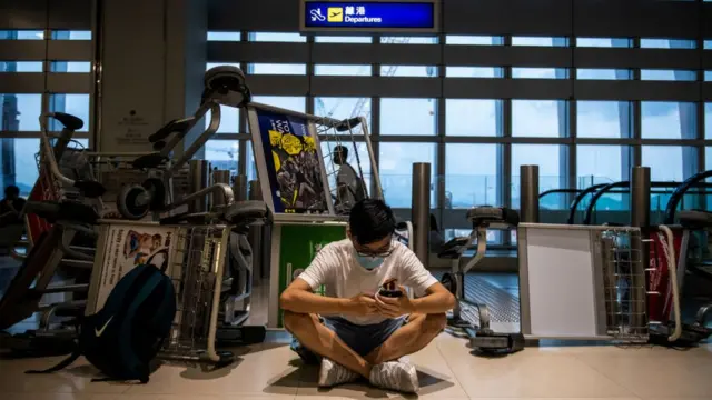 Manifestante viendo su teléfono en el aeropuerto