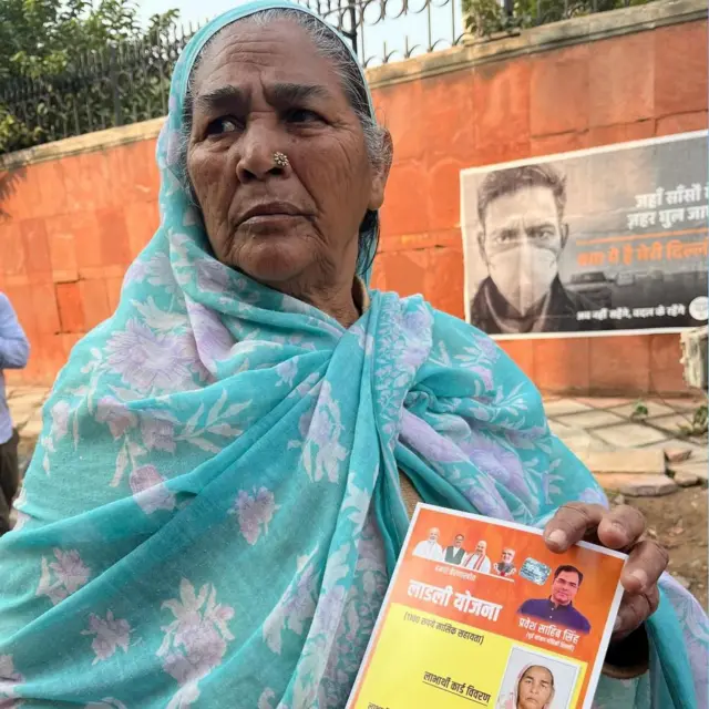 बीजेपी उम्मीदवार से मिला गारंटी कार्ड दिखाती एक महिला