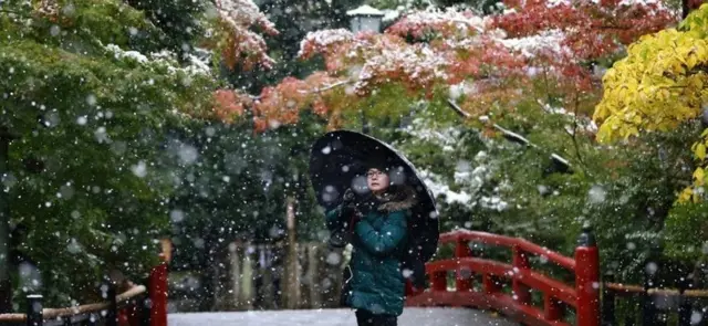 A visitor takes a photo in the snow at the Tsurugaoka Hachimangu Shrine in Kamakura, near Tokyo