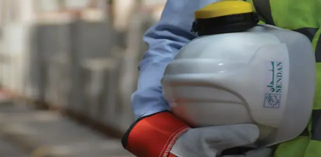 सेन्डान इन्टर्न्याश्नल कम्पनीको लोगो अङ्कित हेल्मेट बोकेका कामदारको हात