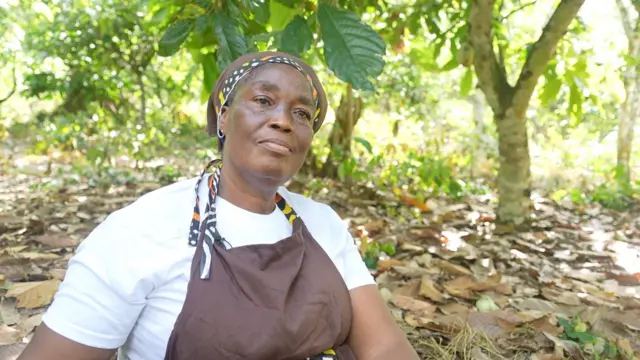 Nathalie Dago assise dans sa plantation de cacaoyers