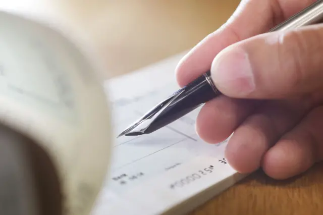 Hand writing cheque - stock photo