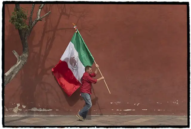 Bandera mexicana flamea en las manos del escritor español Ignacio Martínez de Pisón