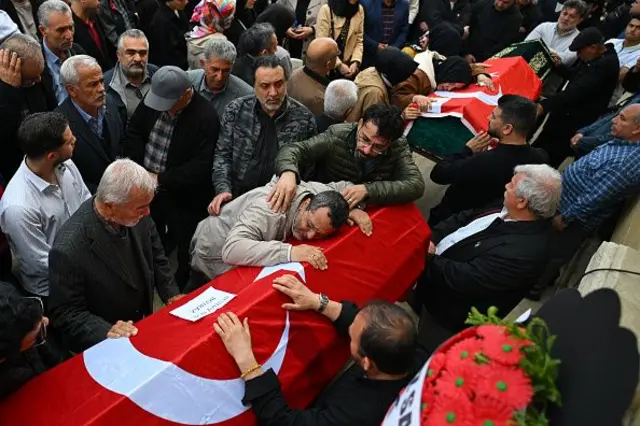 Türk bayraklı iki tabuta sarılan yaslı aileleri cenaze töreninde. 