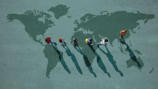 একটি প্রতীকী ছবি যেখানে বিশ্বের মানচিত্রের ছাপ থাকা একটি জায়গার ওপর দিয়ে হেঁটে যাচ্ছে ছয়জন মানুষ