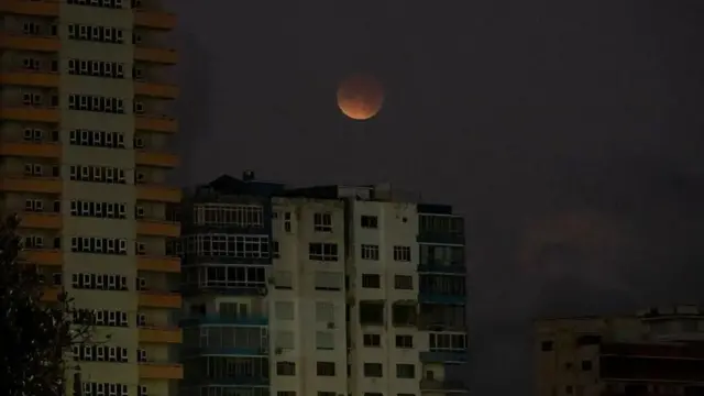 چند ساختمان در هاوانا در شب که در خاموشی هستند و ماه بدر در آسمان دیده می‌شود