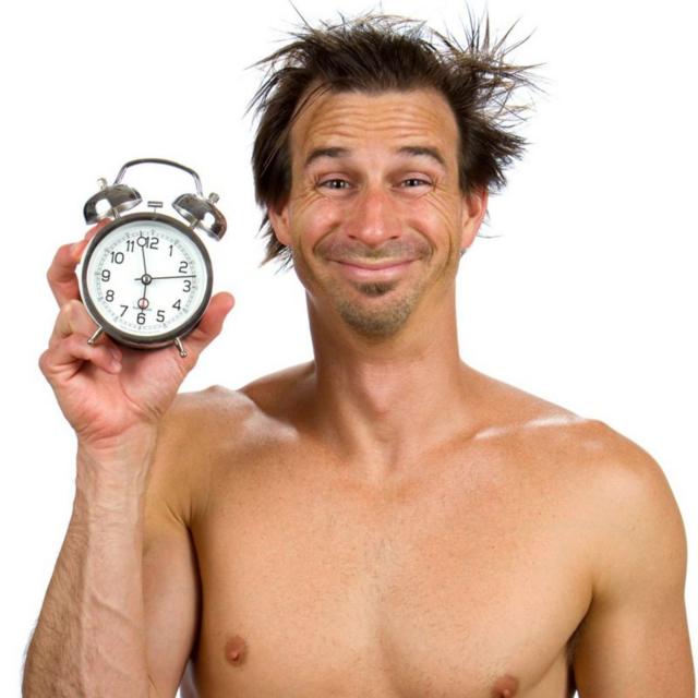 Homem sem camisa segurando um relógio