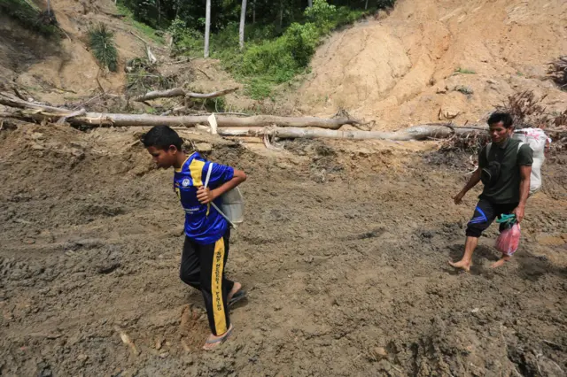 Warga berjalan melintasi Desa Pepelah, Kecamatan Pinding, Kabupaten Gayo lues, Aceh, Senin (22/12/2025).