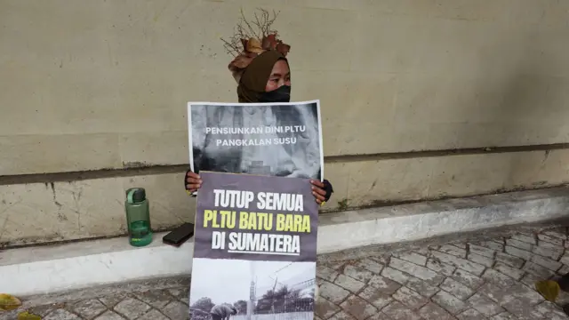 Seorang pengunjuk rasa menyerukan agar PLTU di Sumatera Barat dipensiunkan.
