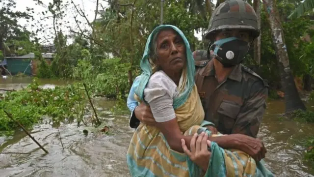 બચાવ કાર્ય કરતા કર્મી એક વૃદ્ધ મહિલાને બચાવી રહ્યા છે.